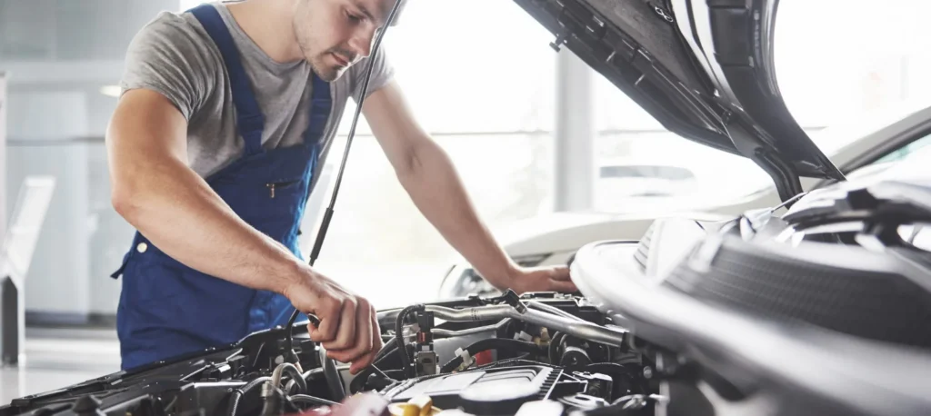 Técnico revisando motor de vehículo durante servicio de auxilio mecánico en taller.